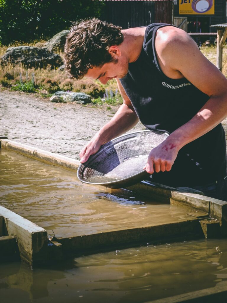 Person gently measuring a fish on a wet board beside a stocked pond with a notebook and thermometer.